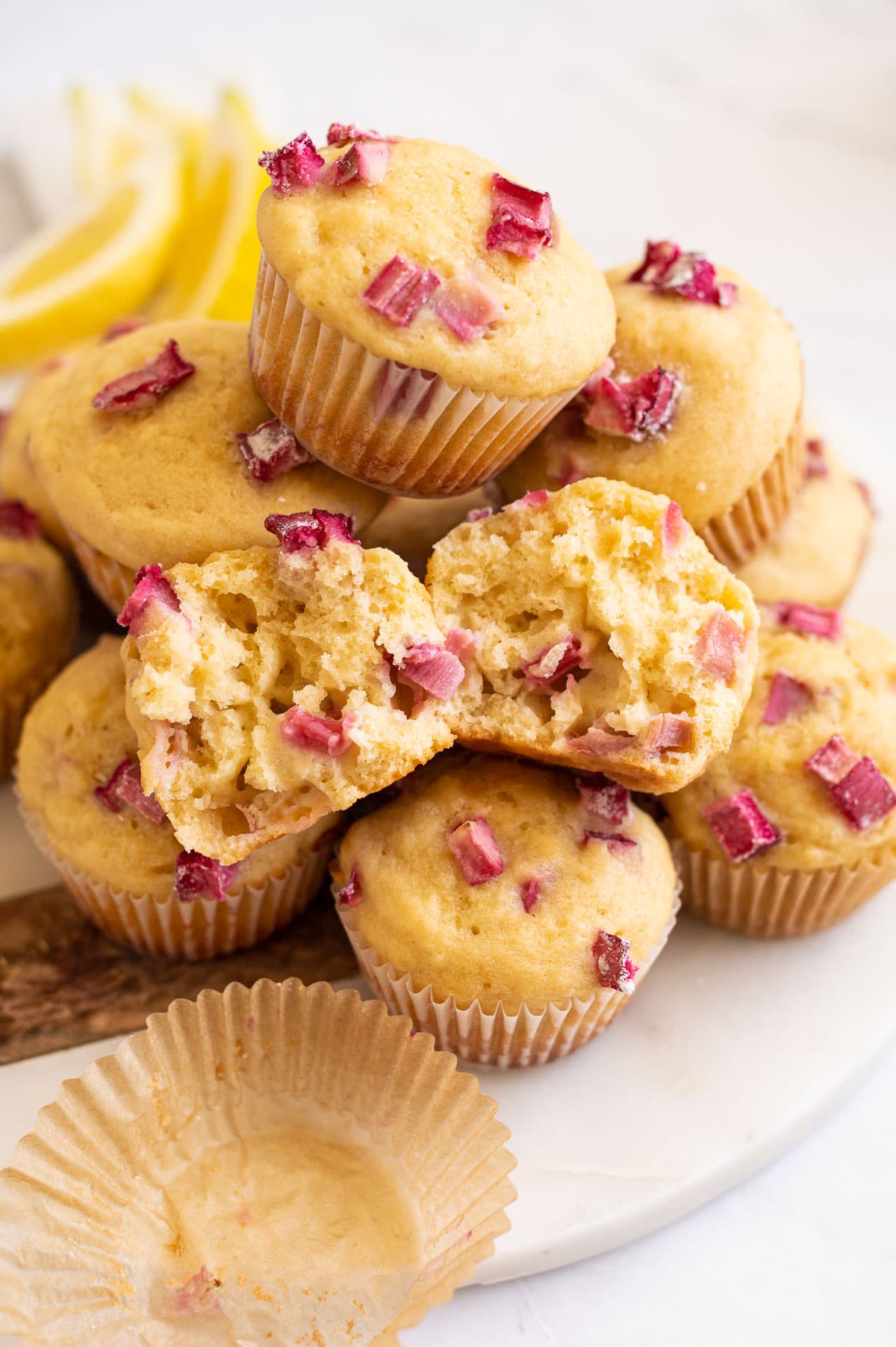 Rhubarb muffin showing texture inside on a pile of muffins.