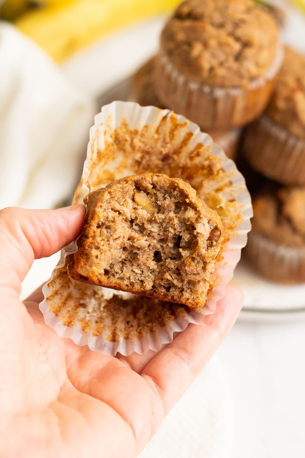 Person holding a banana muffin  showing texture inside.