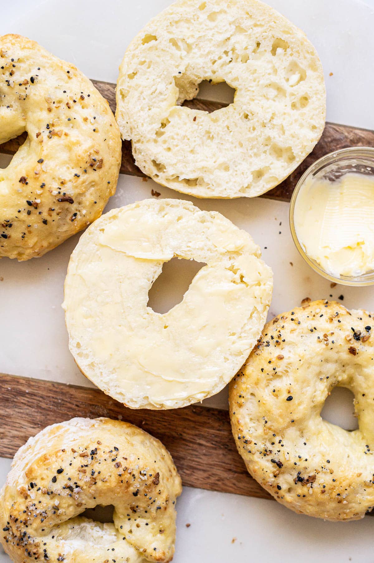 Sliced bagel with cottage cheese and smeared with butter. More protein bagels around.