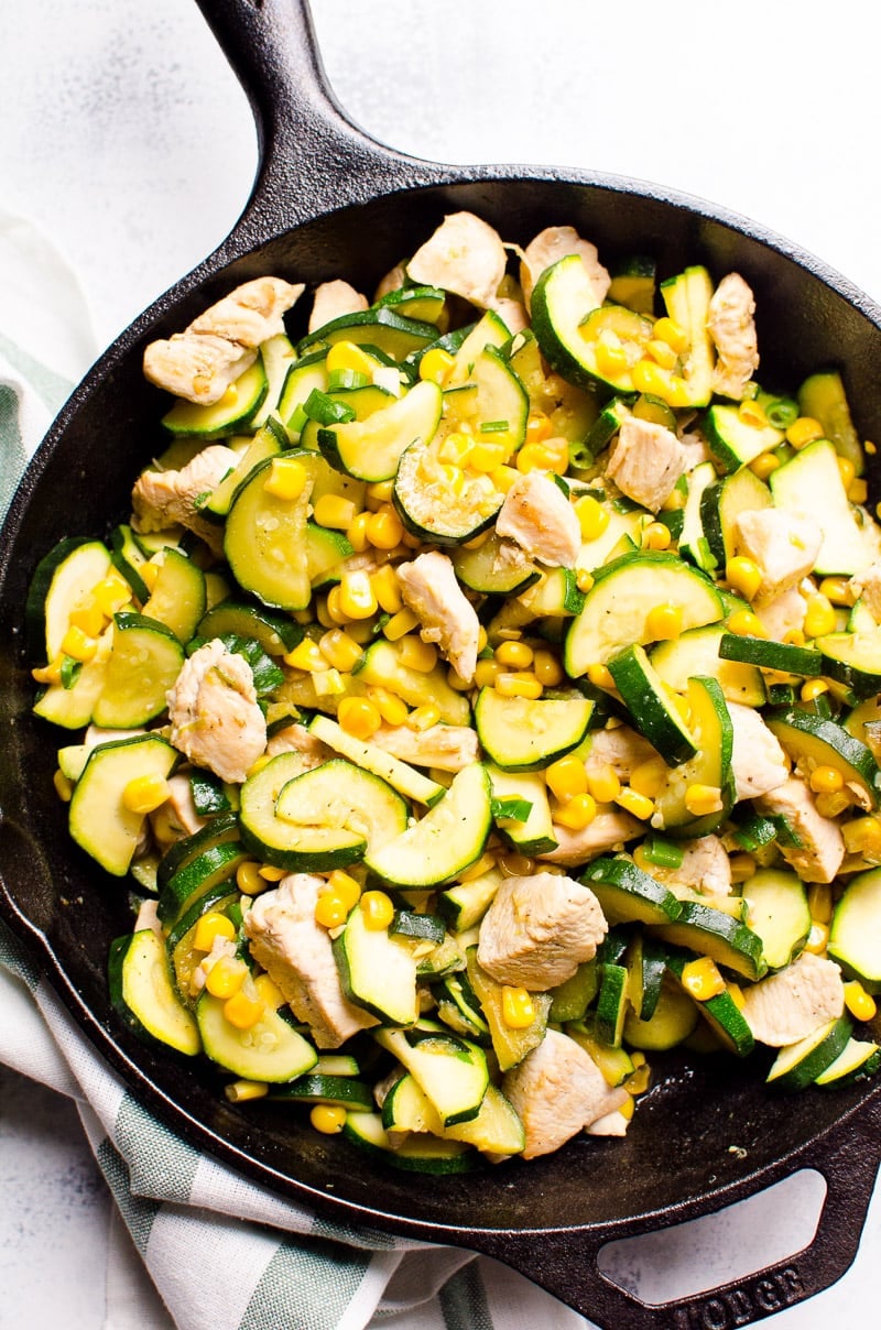 Chicken and corn cooked with zucchini and garlic in cast iron skillet.