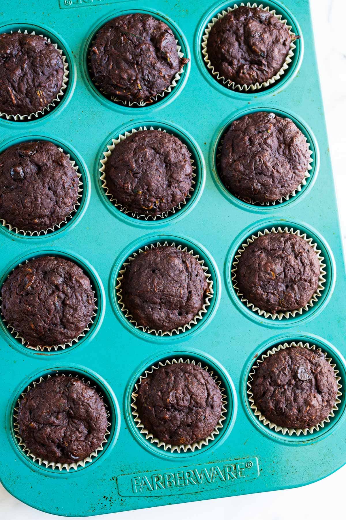 Chocolate zucchini muffins in a blue muffin tin.
