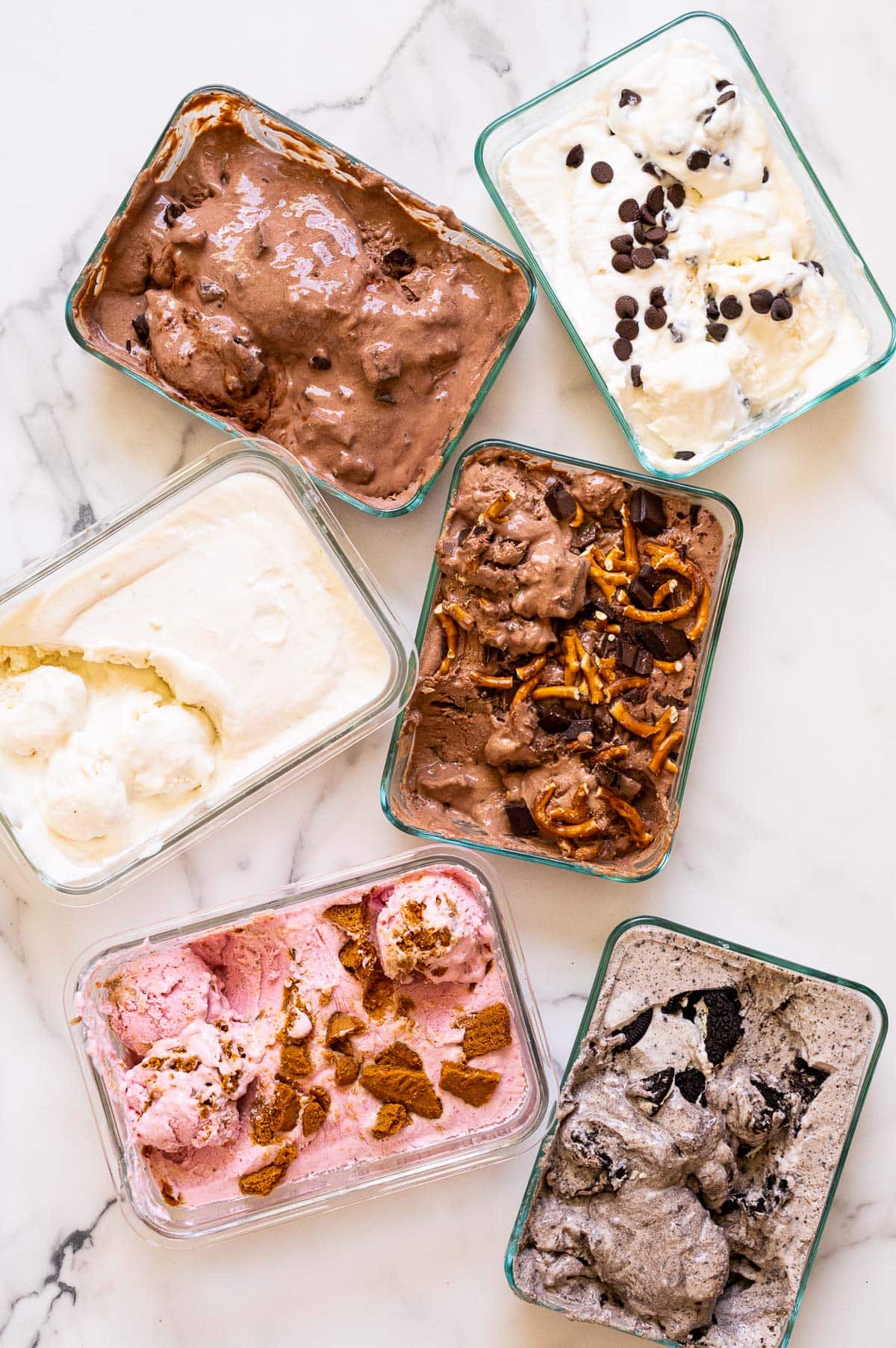 Cottage cheese ice cream of six flavors in glass containers on a countertop.