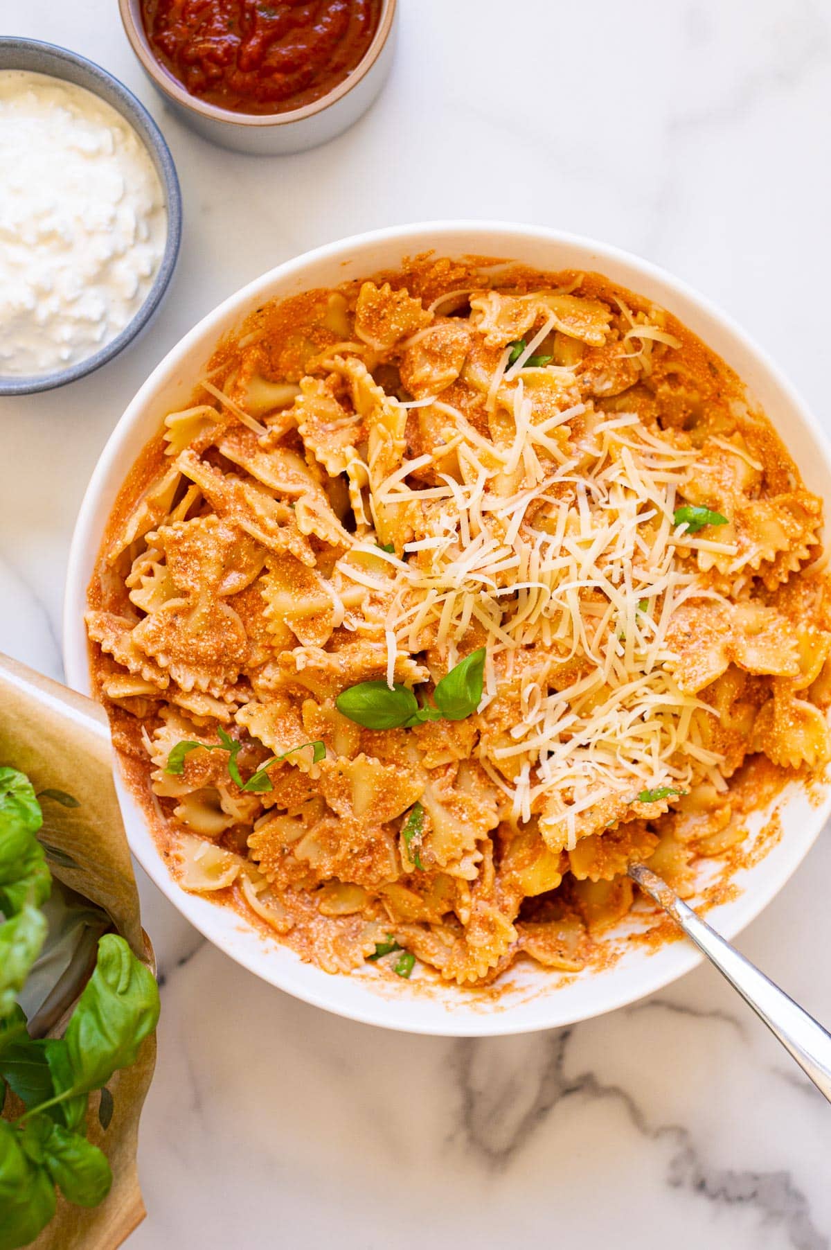 Cottage cheese pasta sauce served with pasta, cheese and fresh basil in a bowl with a spoon.