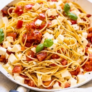 Caprese pasta with mozzarella and basil in a skillet.