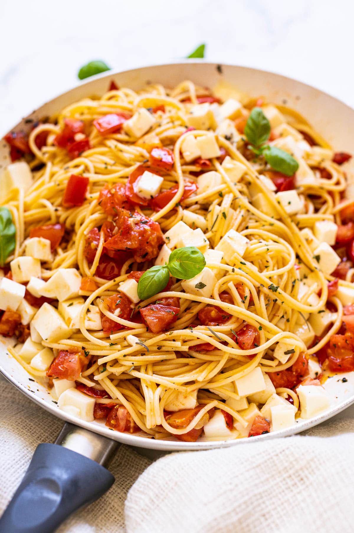 Caprese pasta with mozzarella and basil in a skillet.