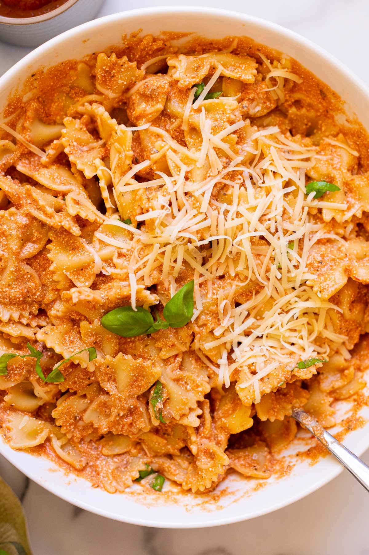 Cottage cheese pasta served in a bowl garnished with basil and cheese.