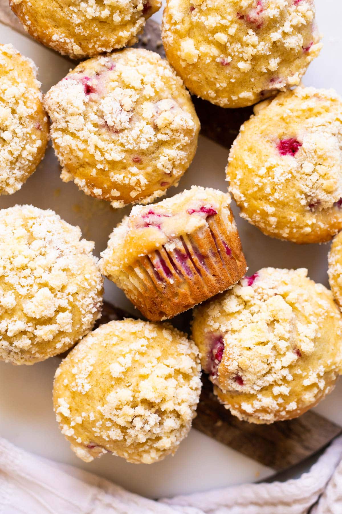 Raspberry muffins on a platter was one muffin laying on the side.