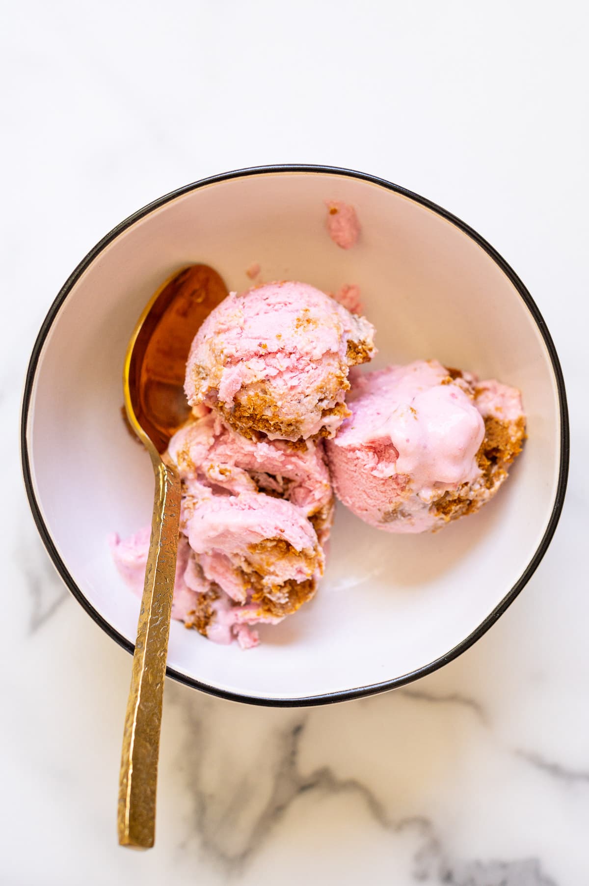 Strawberry cheesecake cottage cheese ice cream scoops in a bowl.