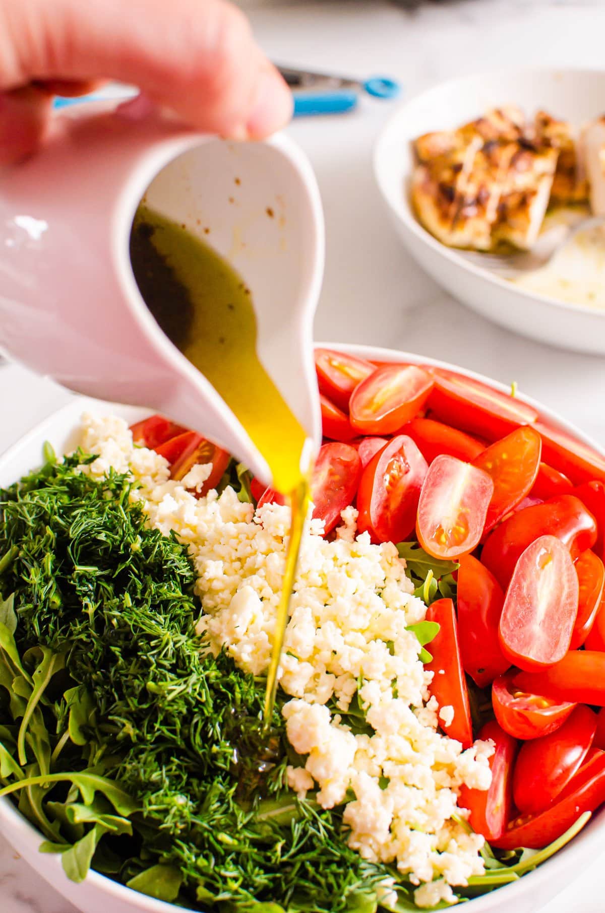 Arugula feta salad with tomatoes and dill drizzled with balsamic dressing in a bowl.