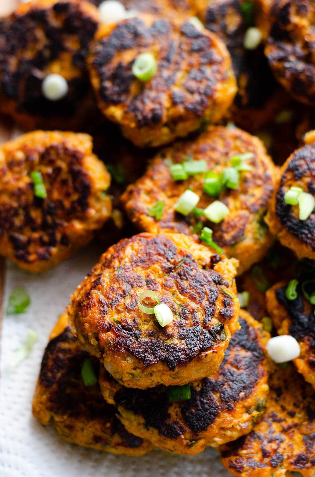 Canned salmon cakes garnished with green onion and served on a platter.