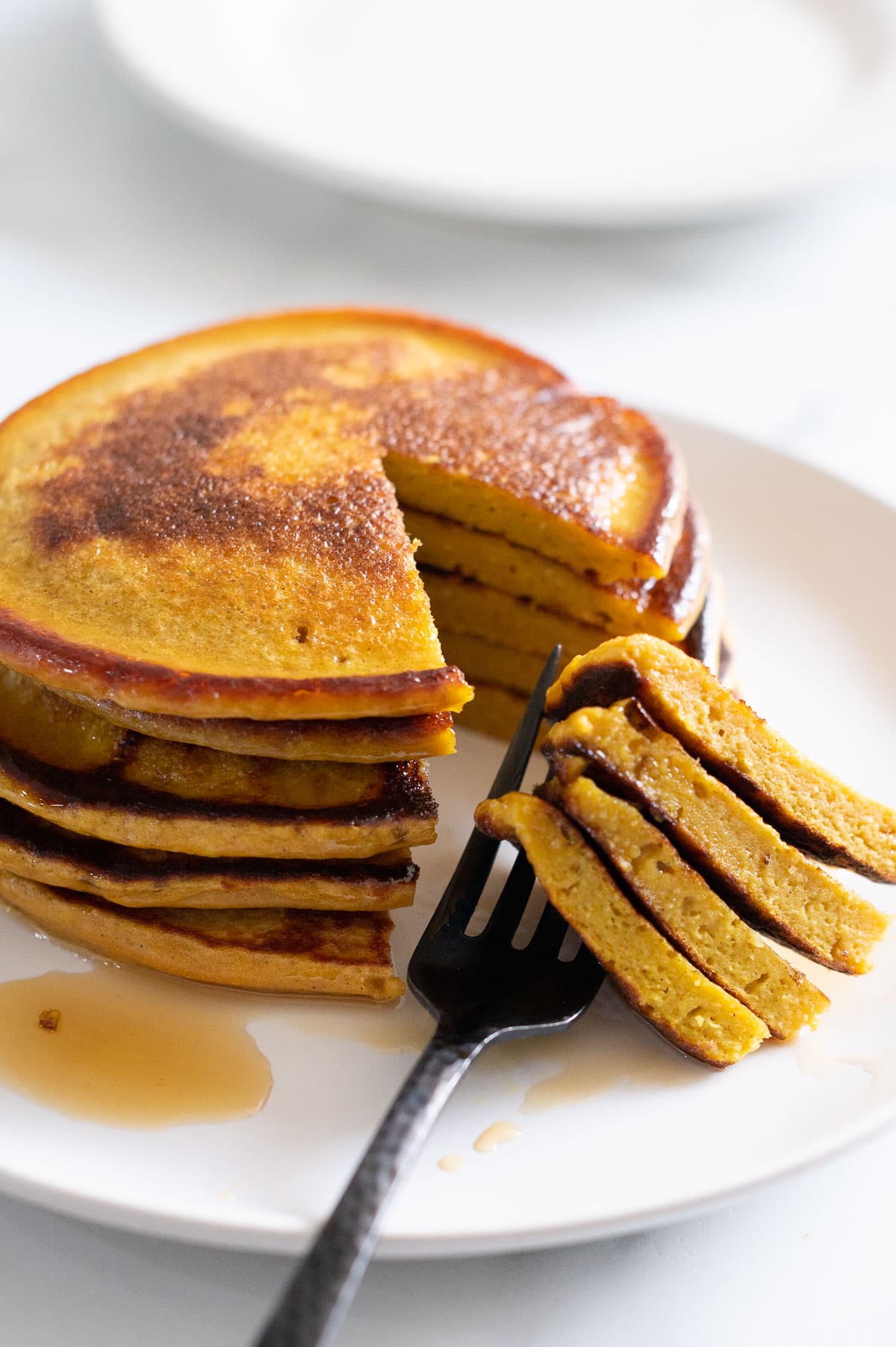 A stack of cottage cheese pancakes cut into and showing texture inside.