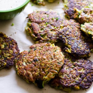 Fried tuna zucchini cakes served with dipping sauce on parchment paper.