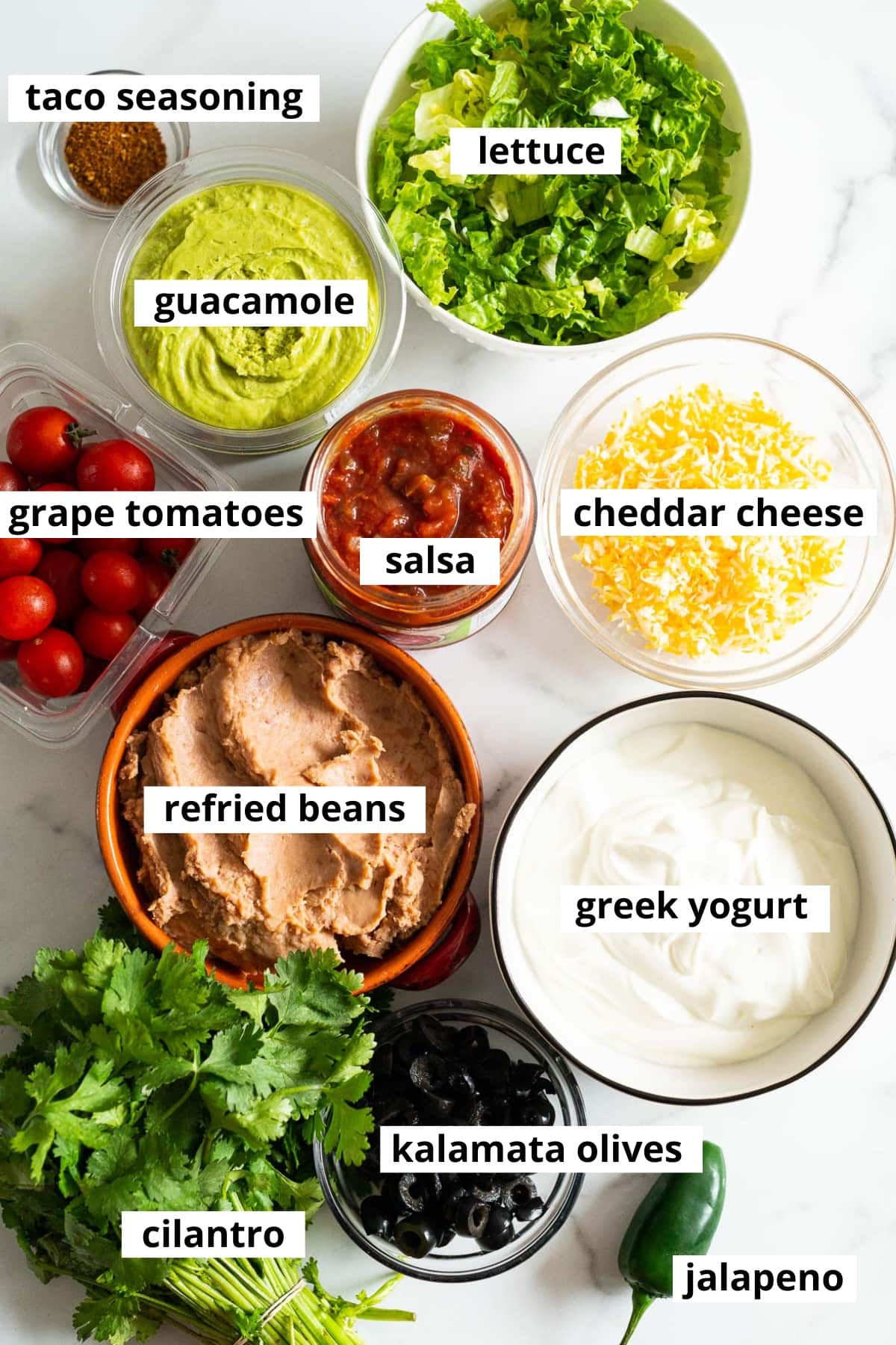 Lettuce, guacamole, taco seasoning, cheddar cheese, salsa, grape tomatoes, refried beans, Greek yogurt, kalamata olives, cilantro, jalapeno.