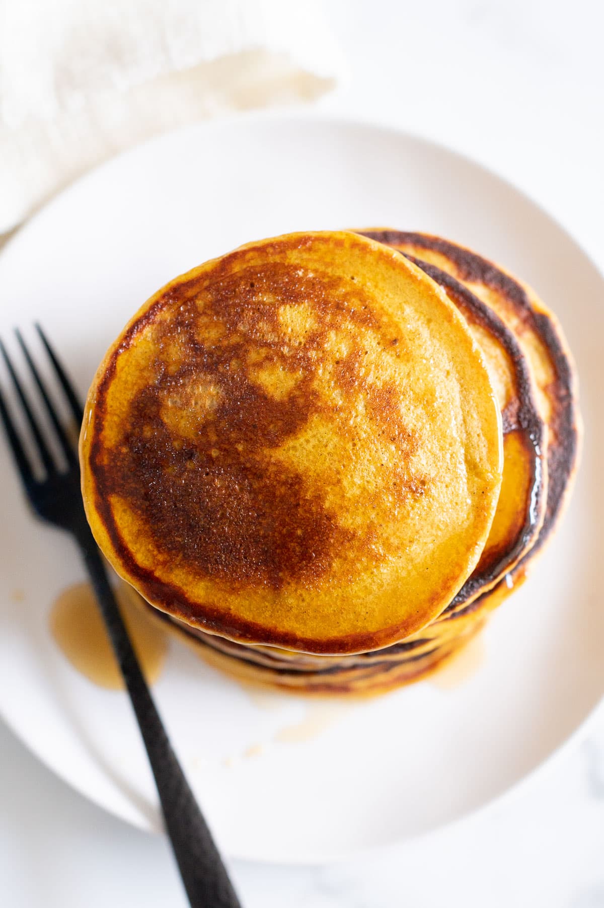 Looking down on a stack of cottage cheese protein pancakes served on a plate with syrup.