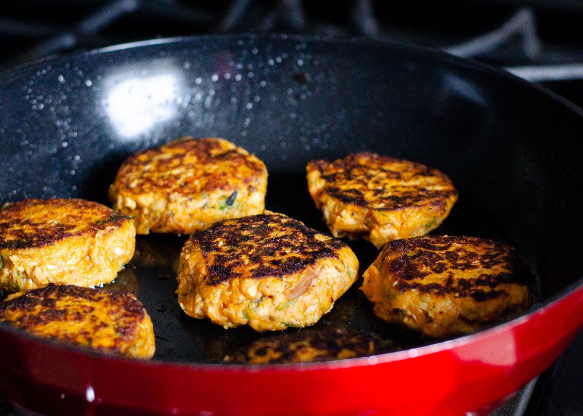 Salmon  frying on a skillet with oil.