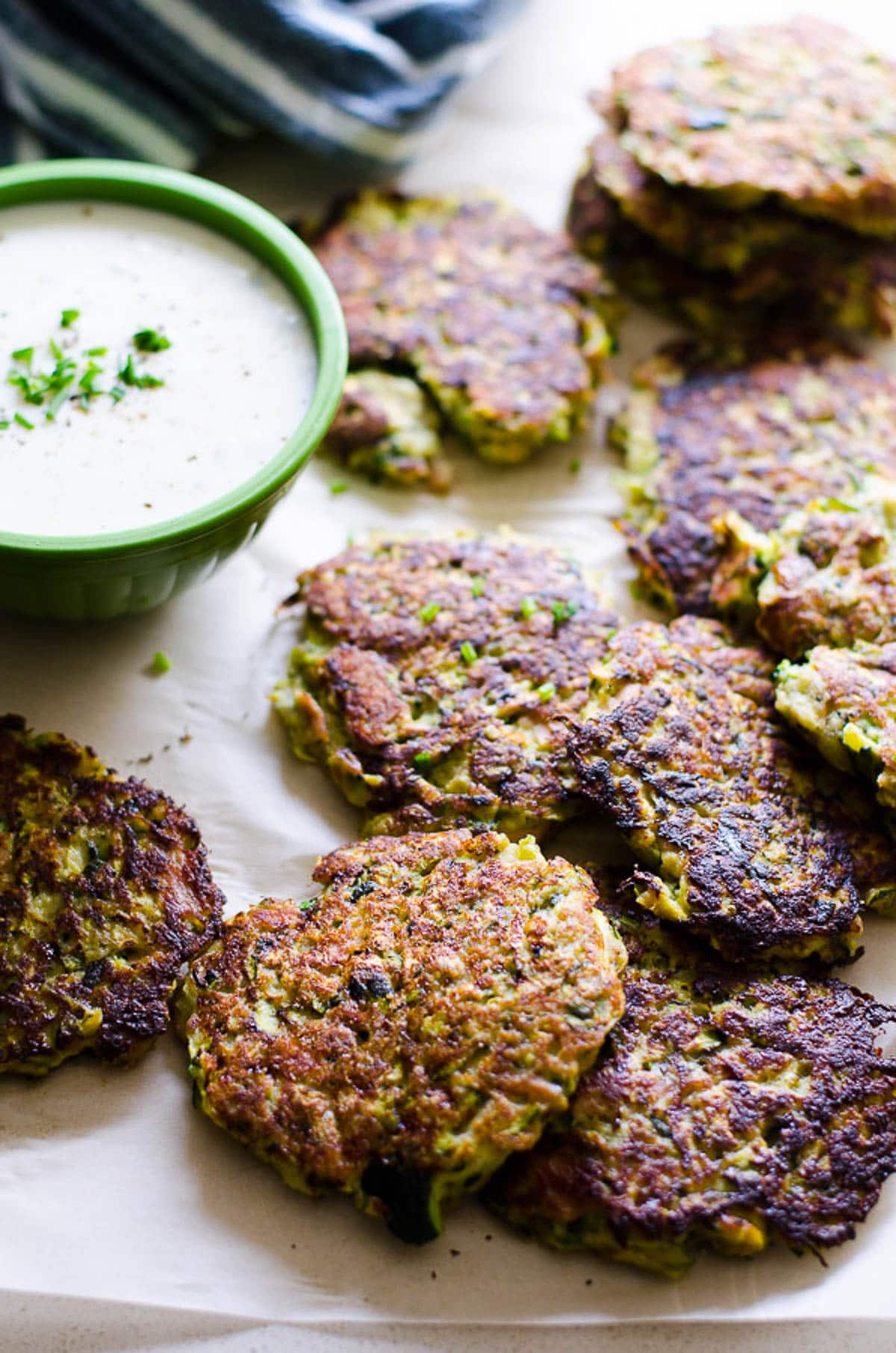 Fried tuna zucchini cakes served with dipping sauce on parchment paper.