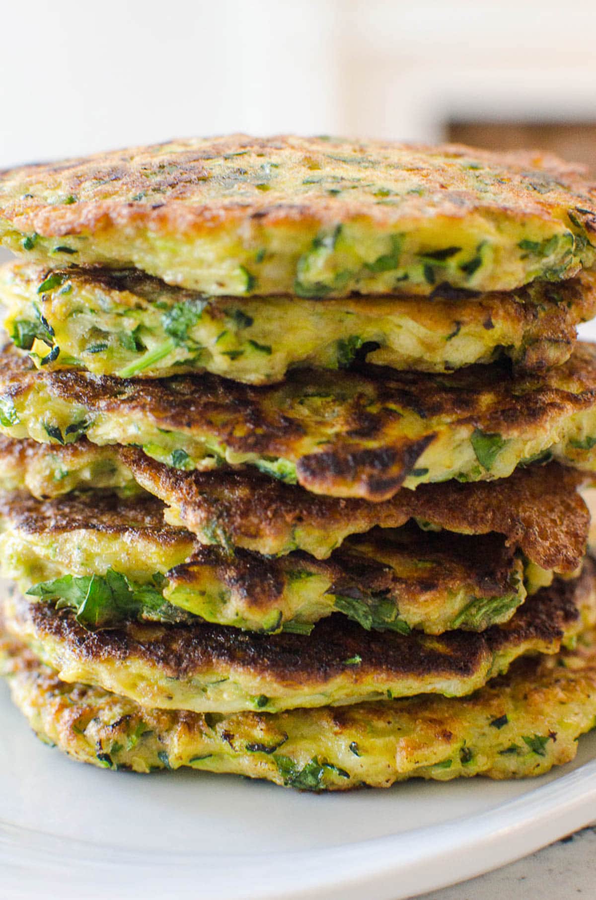 Closeup of baked zucchini fritters showing texture with lots of parsley stacked.