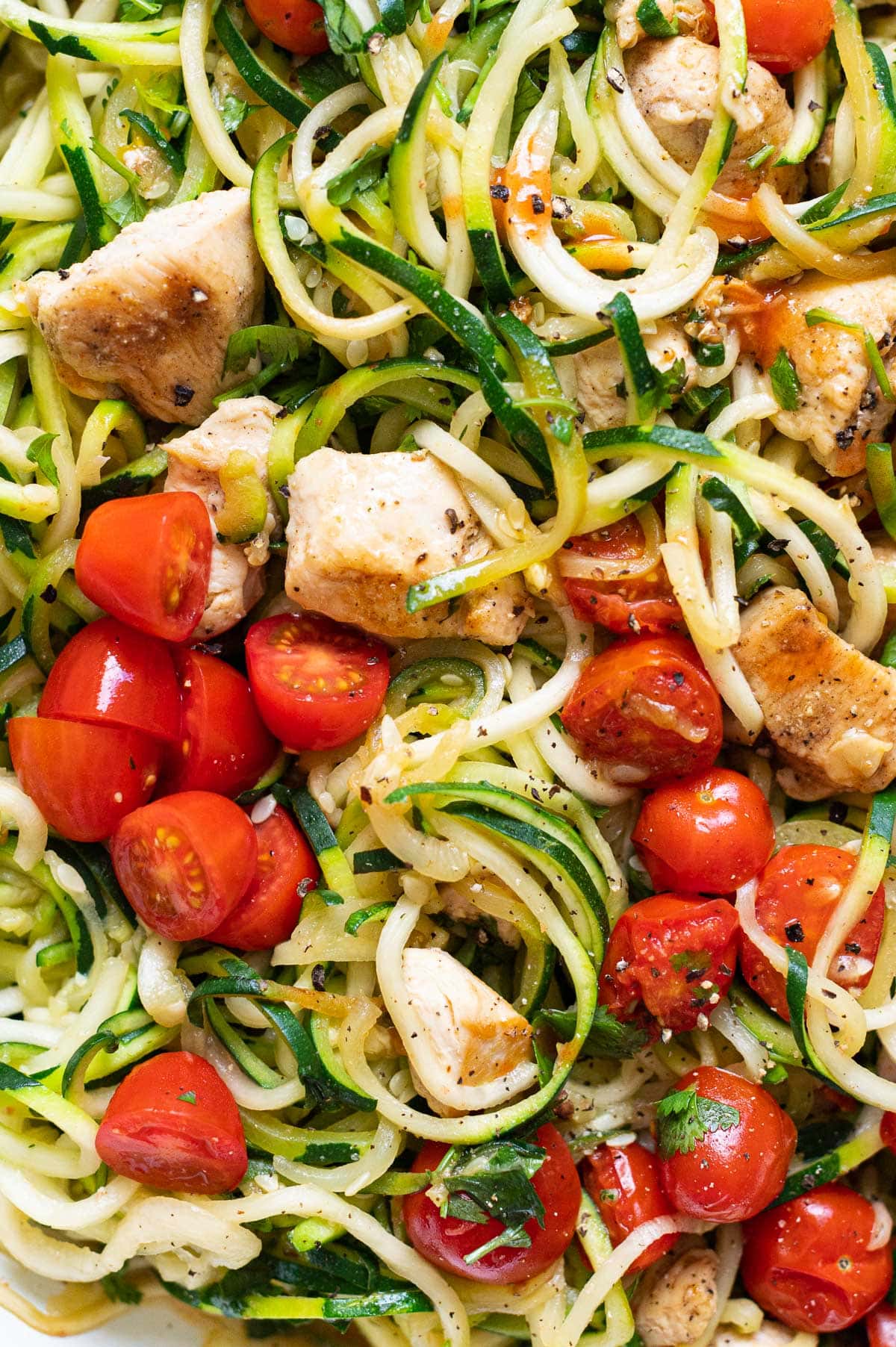 Close up of zucchini noodles with chicken and grape tomatoes.