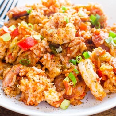 Instant pot Jambalaya garnished with green onion and served on white plate with a fork.