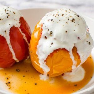 Instant pot stuffed peppers served with yogurt and ground black pepper on top with juices on a plate.