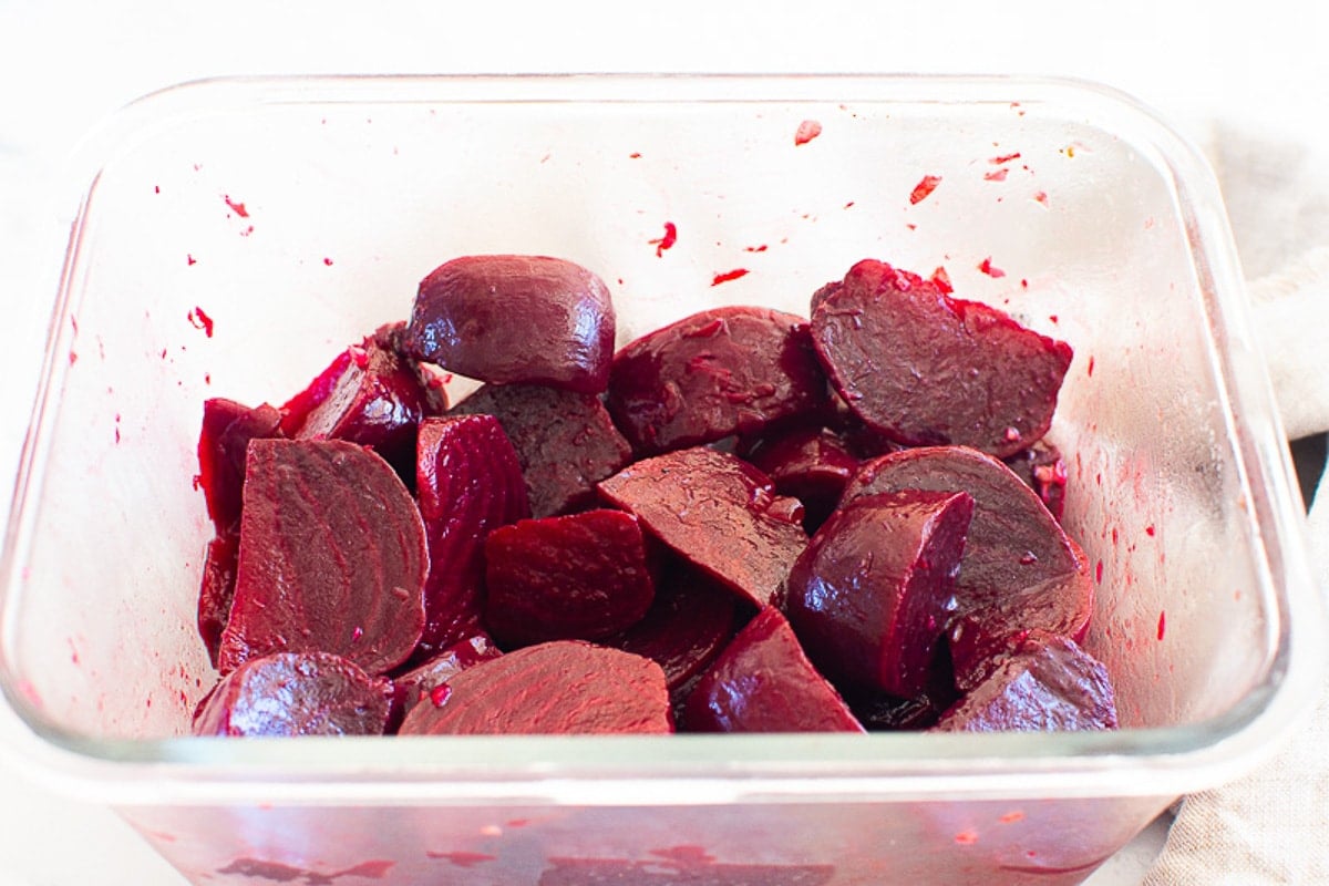 Chopped cooked instant pot beets with oil and vinegar in a glass container.