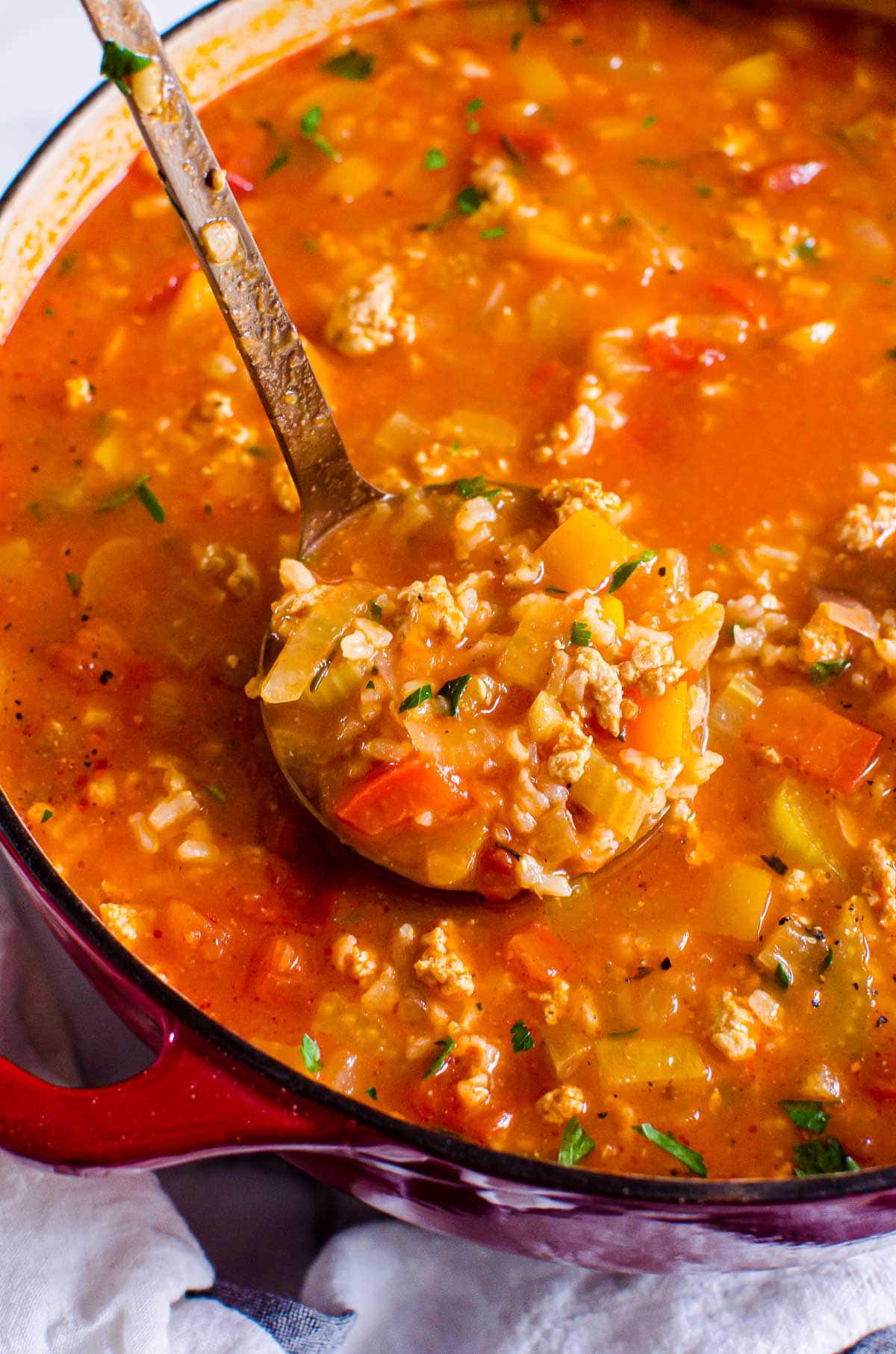 Stuffed bell pepper soup on a ladle above the pot.