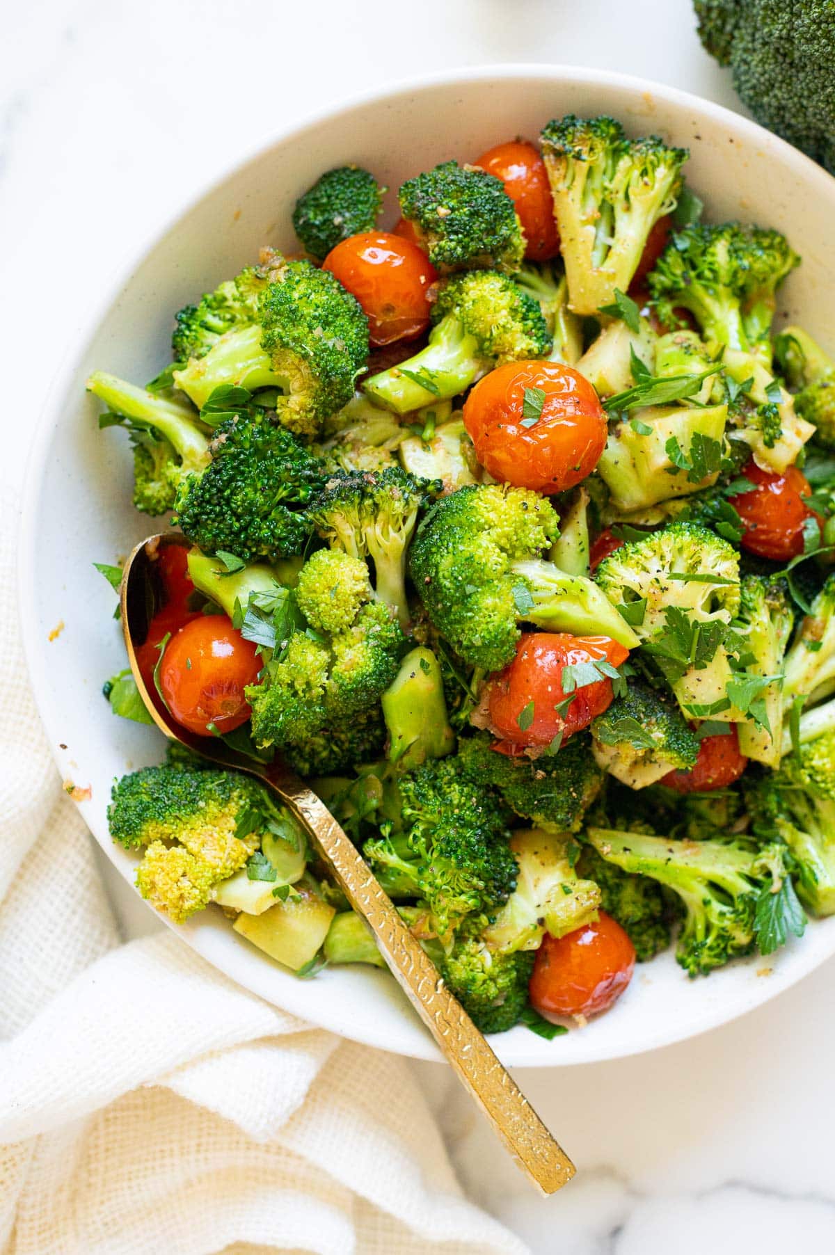 Sauteed broccoli with tomatoes in a bowl with a spoon.