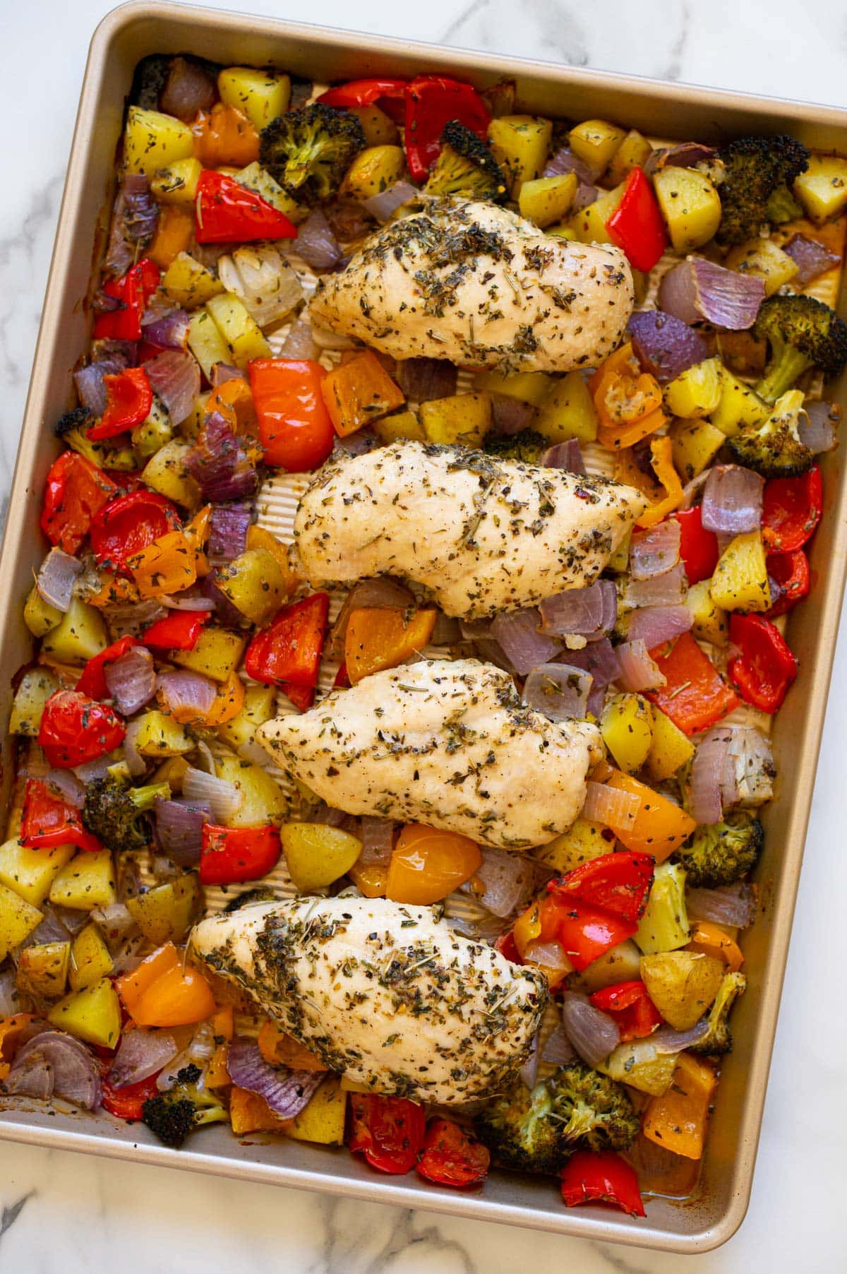 Sheet pan chicken and veggies on kitchen counter.