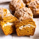 Pumpkin cream cheese muffin sliced in half showing texture and filling inside.