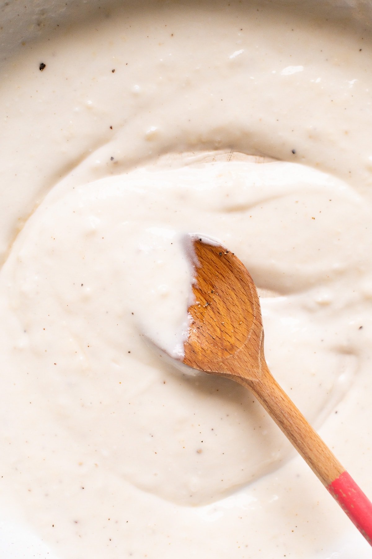 Healthy alfredo sauce on a wooden spoon.