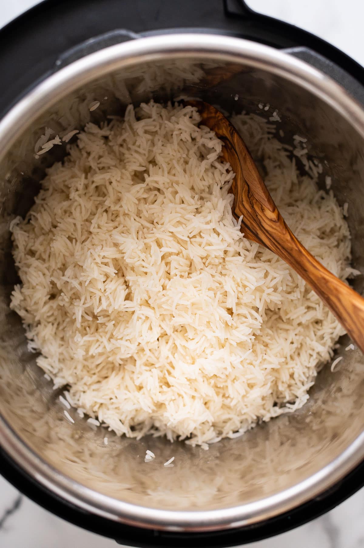 Instant Pot basmati rice in pressure cooker with wooden spoon in it.