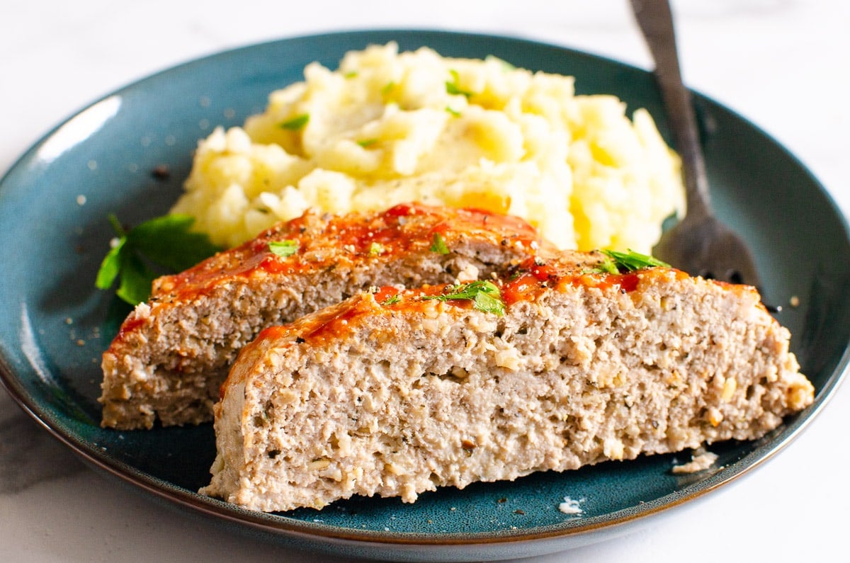 Two slices of instant pot meatloaf served with mashed potatoes on a plate.