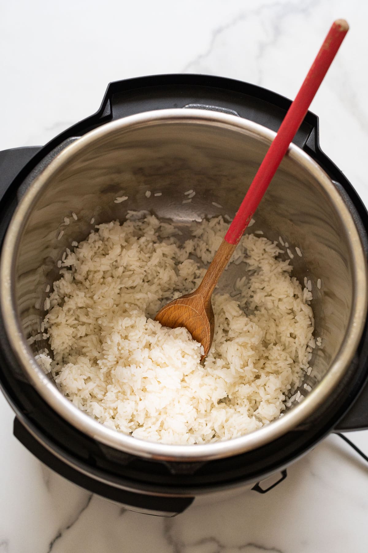 Instant pot white rice with wooden spoon in it.