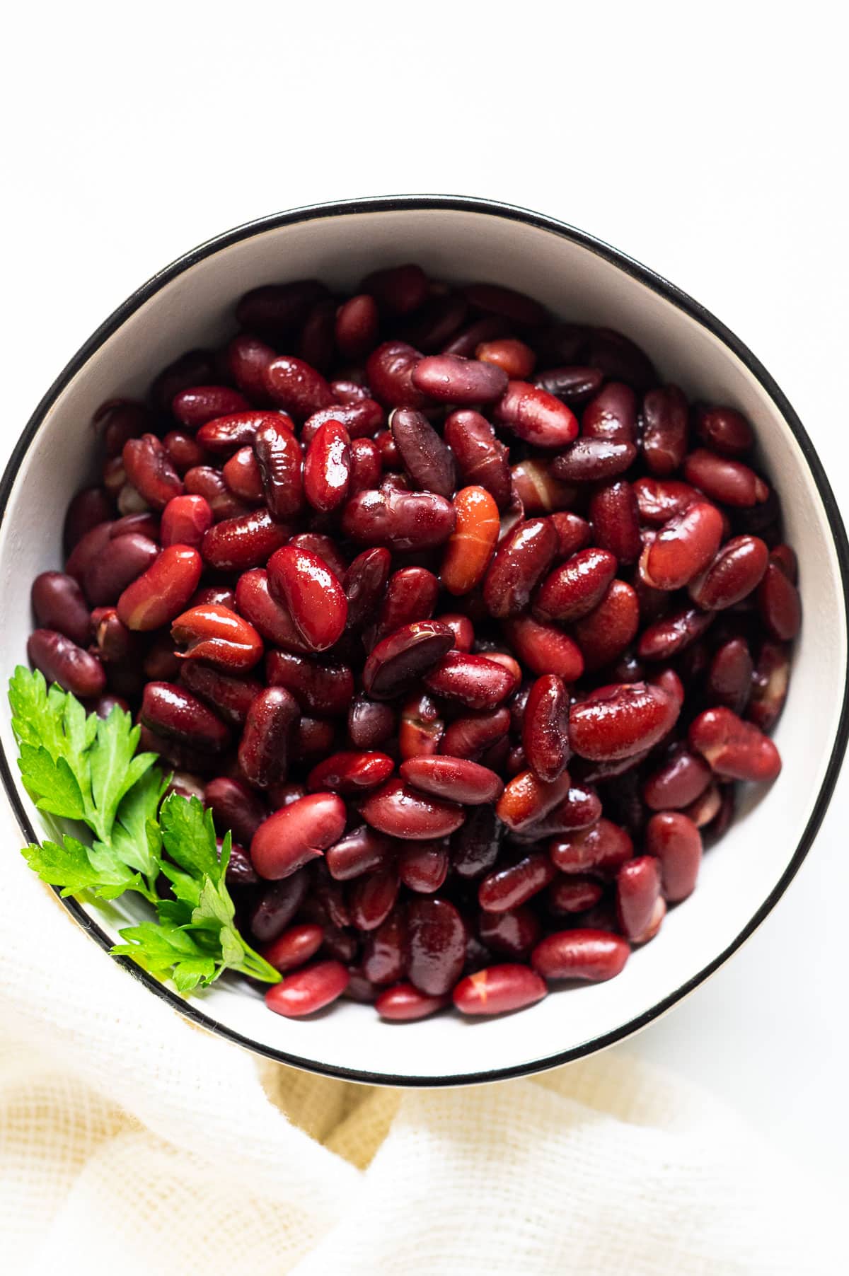 Cooked pressure cooker kidney beans with parsley in white bowl.