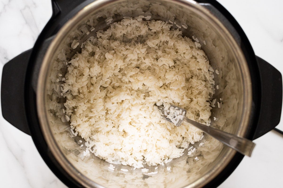 Cooked white rice in Instant Pot fluffed with a fork.