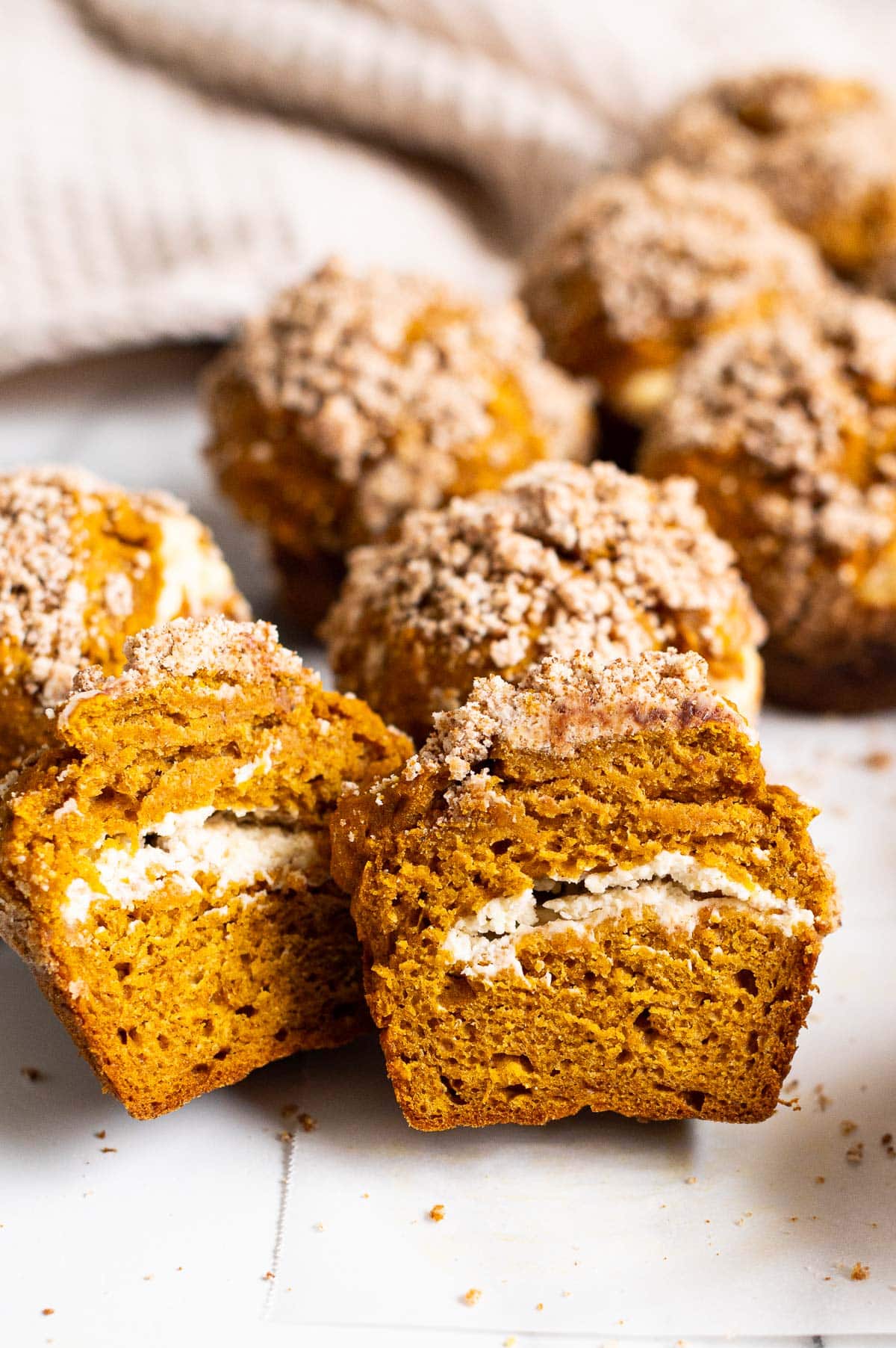 Pumpkin cream cheese muffin sliced in half showing texture and filling inside.