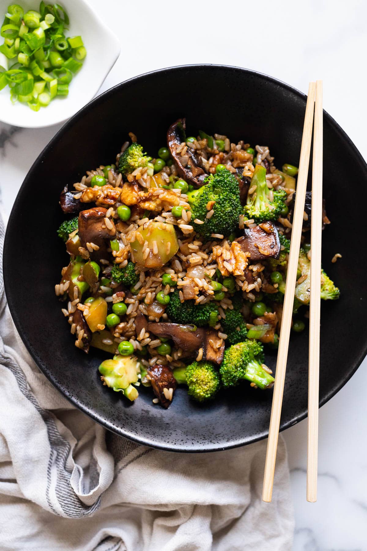 Broccoli mushroom stir fry served in a black bowl with chopsticks.