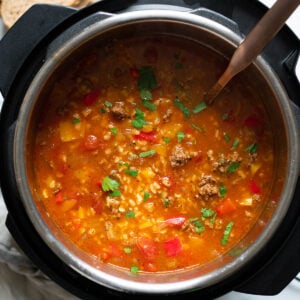 Instant Pot stuffed pepper soup garnished with parsley and soup ladle inside the pot.