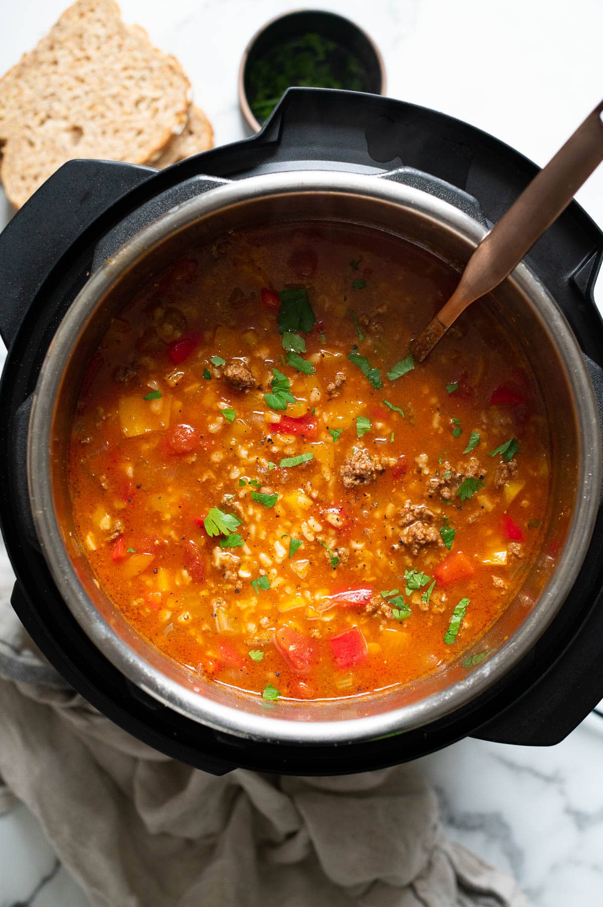 Instant Pot stuffed pepper soup garnished with parsley and soup ladle inside the pot.