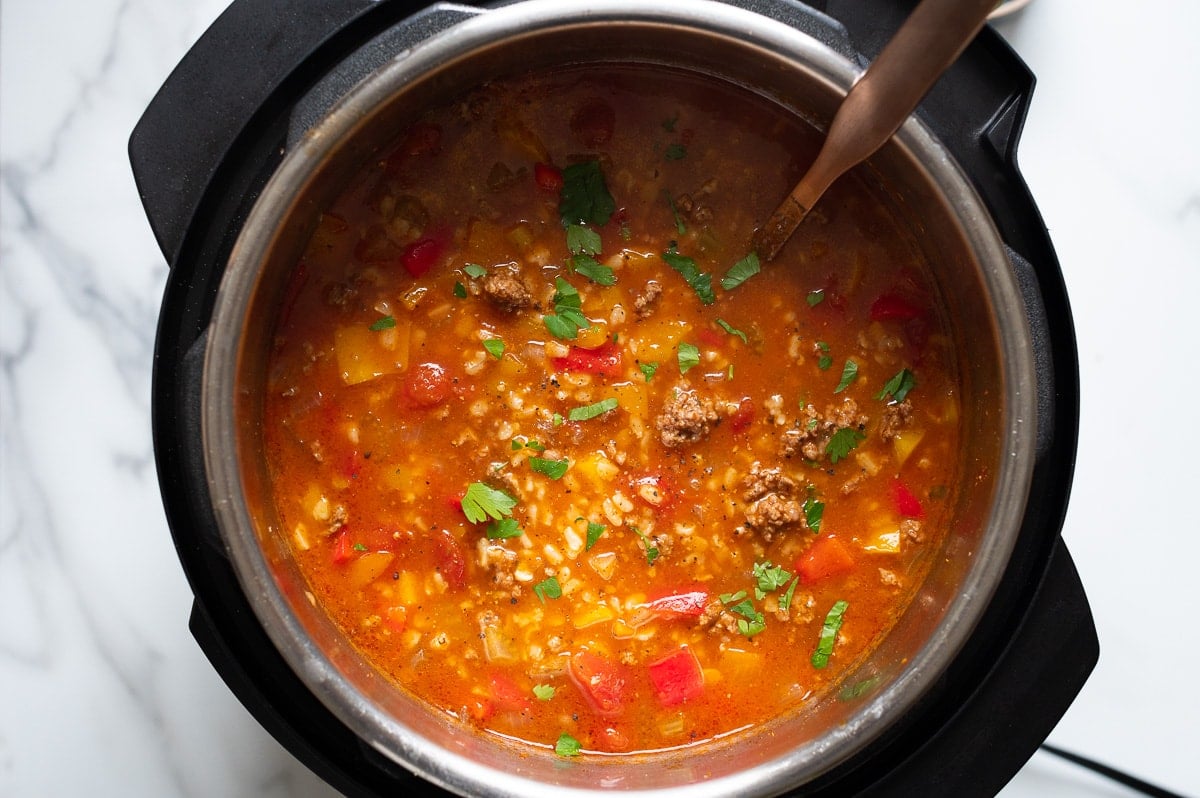 Cooked stuffed pepper soup in pressure cooker with soup ladle.