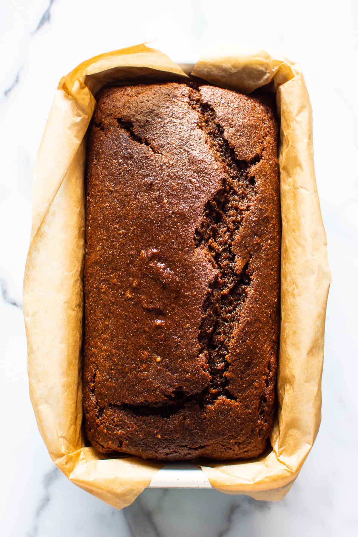 Healthy gingerbread loaf in a loaf pan lined with parchment paper.