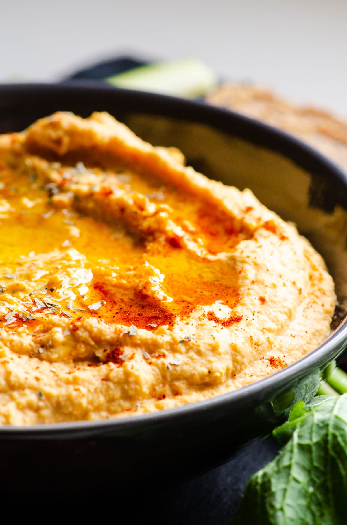 Side view of a bowl of sweet potato hummus result with olive oil and sprinkled with smoked paprika.