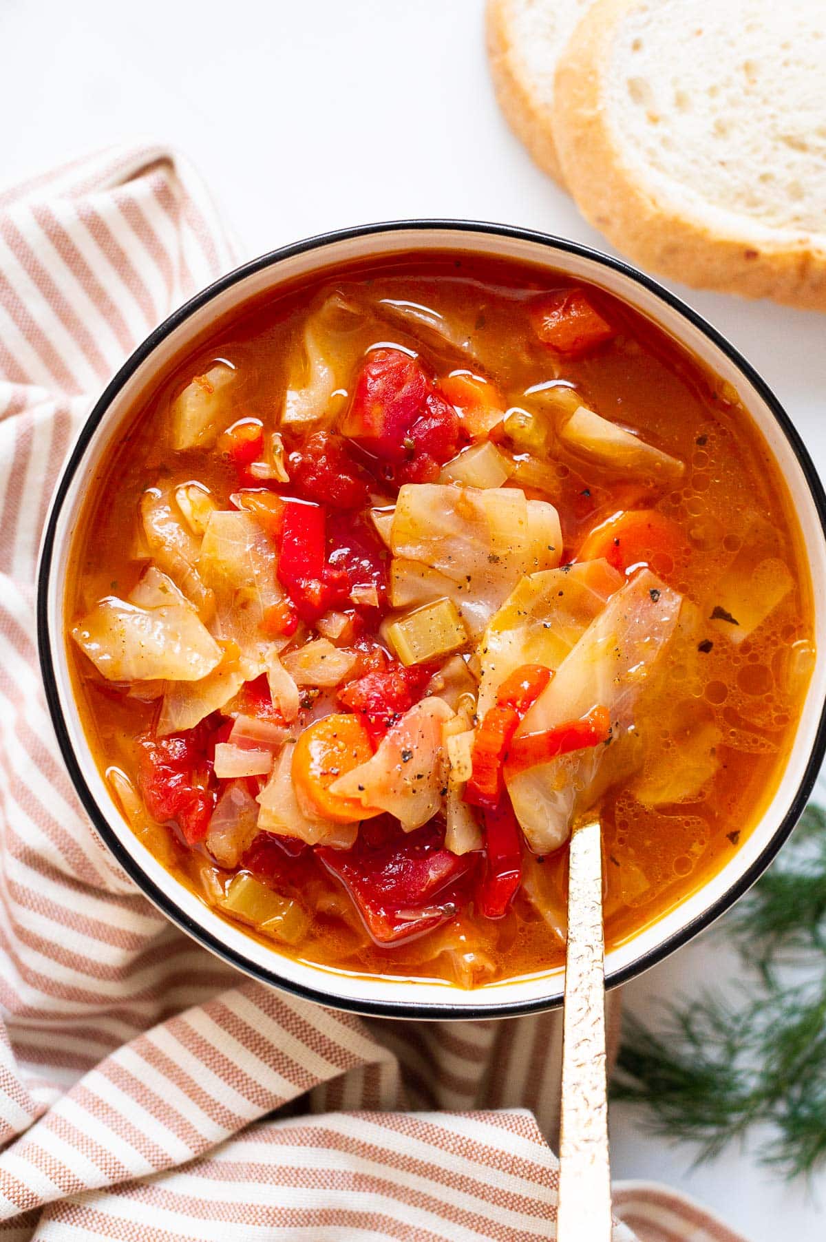 Pressure cooker cabbage soup with tomatoes and carrots served in a bowl with a spoon.