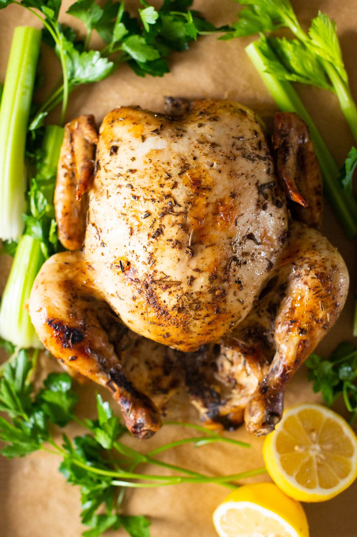 Slow cooker whole chicken with vegetables and lemon on a tray.