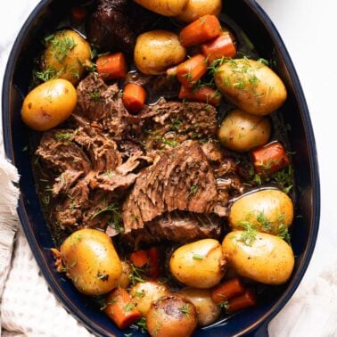 Instant pot sirloin tip roast with carrots and baby potatoes served in baking dish.
