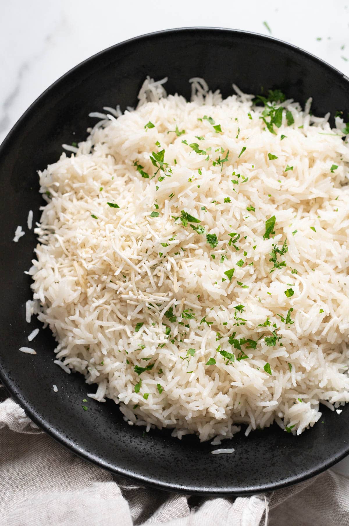 Instant pot coconut rice garnished with coconut flakes and cilantro in black bowl.