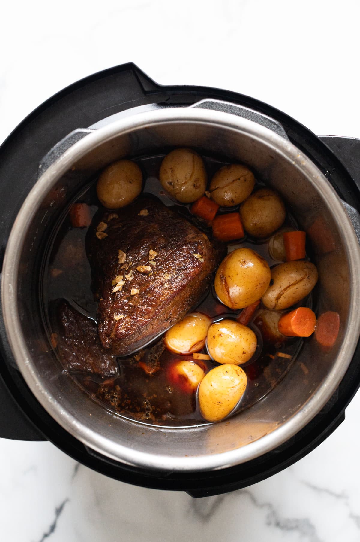 Sirloin tip roast in instant pot with carrots and baby potatoes in au jus.