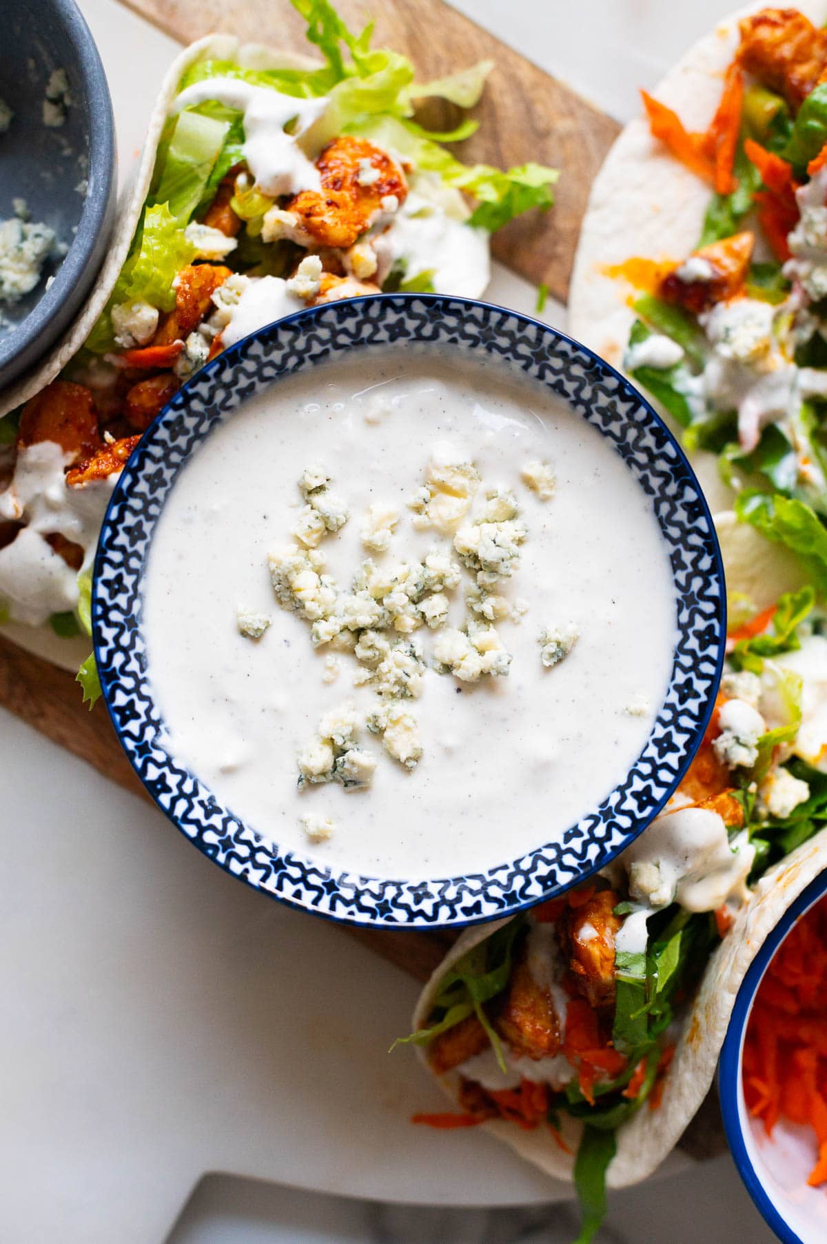 Yogurt blue cheese dressing with crumbled blue cheese in a bowl served with tacos.