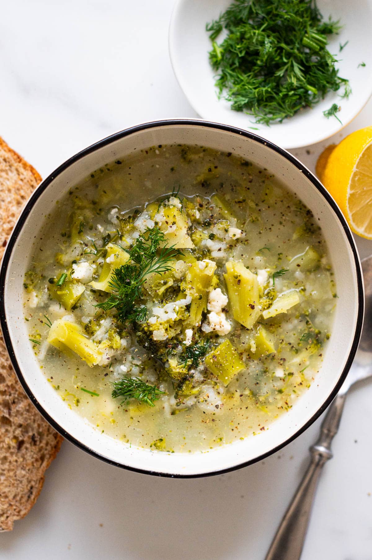Broccoli feta soup garnished with dill and pepper and served in a bowl.