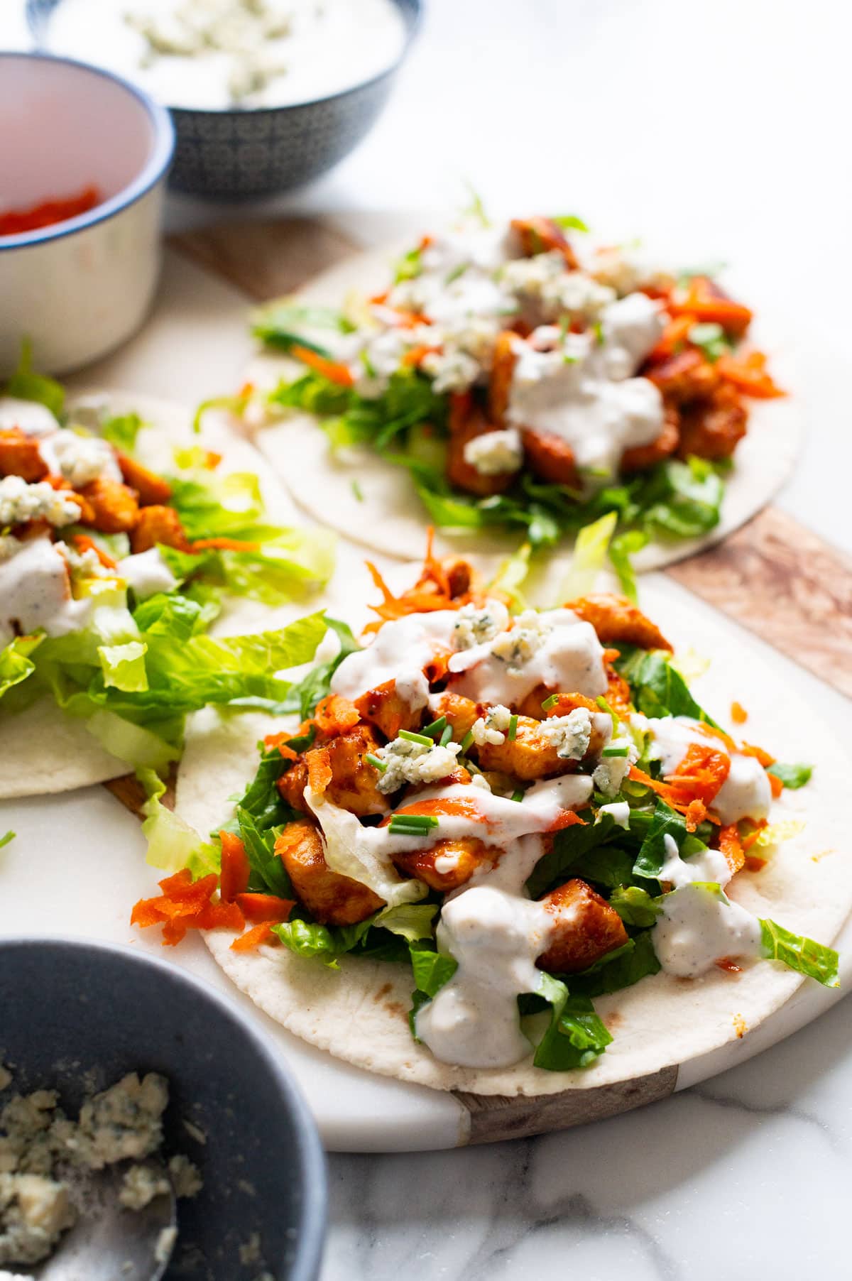Buffalo chicken tacos with blue sauce, carrots and lettuce.